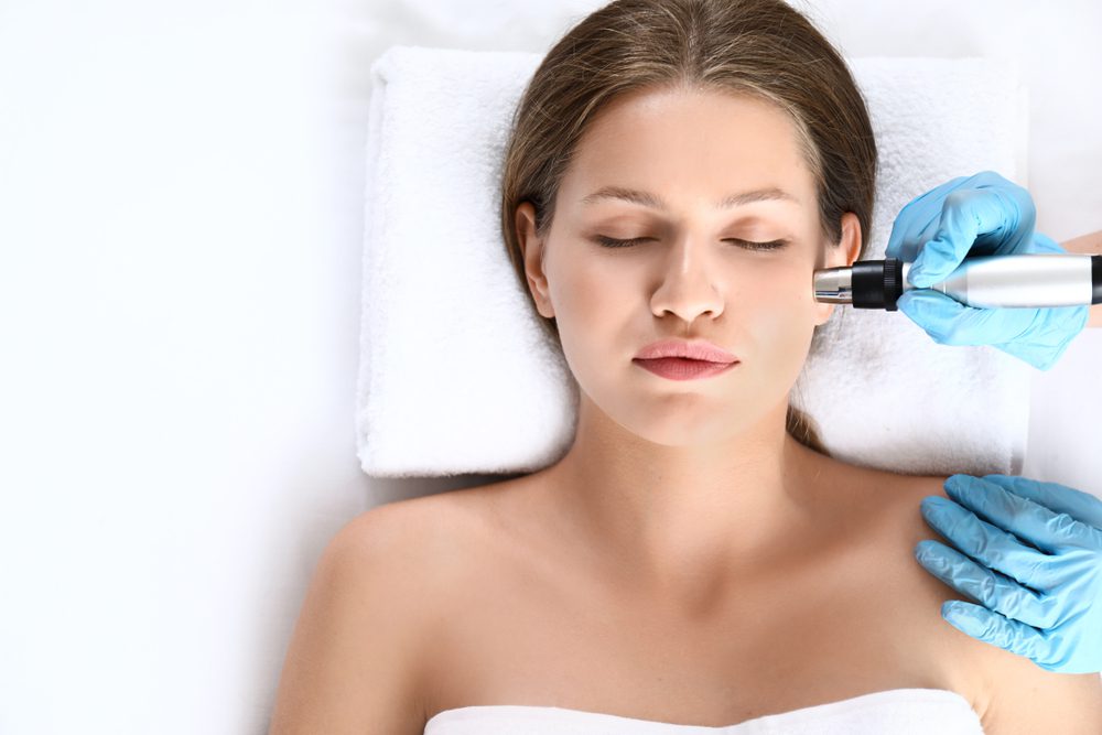 A woman getting her face cleaned with an electric device.